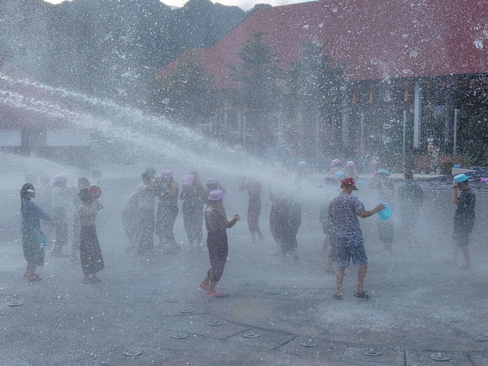 Visitors playing in the water splash area under the karst mountains